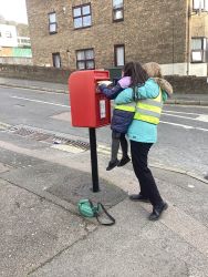 Child posting a letter in a post box.